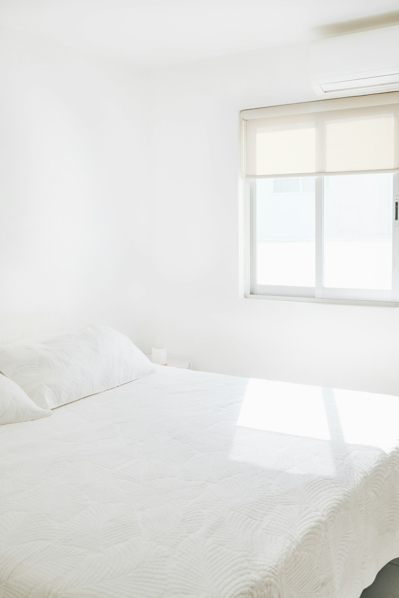 Sunlit bedroom with crisp, freshly made white bedding in a spotless Round Rock home
